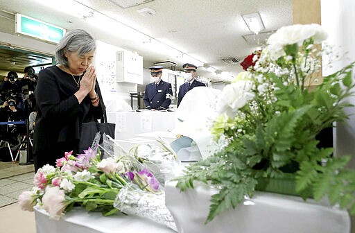 Shizue Takahashi, the wife of a subway worker killed in the March 20, 1995 sarin gas attack, prays as she lays flowers on the stand set up at Kasumigaseki subway station in Tokyo Friday, March 20, 2020. Tokyo subway officials marked a moment of silence in memory of victims of the deadly sarin gas attack 25 years ago that killed 13 people. (Kyodo News via AP)