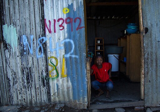 In this photograph taken Thursday March 19, 2020, a woman sits at the entrance of her home in a squatter camp in Soweto, South Africa.  Some countries around the world lack the equipment and trained health workers to respond to the threat of COVID-19 virus. For most people the virus causes mild or moderate symptoms, but for others it causes severe illness.  (AP Photo/Themba Hadebe)