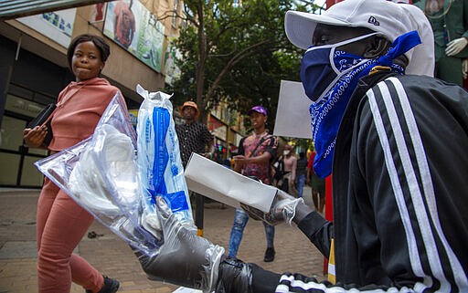 A man wearing a face mask sells masks and gloves in downtown Johannesburg, South Africa, Friday, March 20, 2020. Anxiety rose in Africa's richest nation Friday as South Africa announced coronavirus cases jumped to 202, the most in the sub-Saharan region, while the country's largest airport announced that foreigners would not be allowed to disembark. And state-owned South African Airways suspended all international flights until June. (AP Photo/Themba Hadebe)