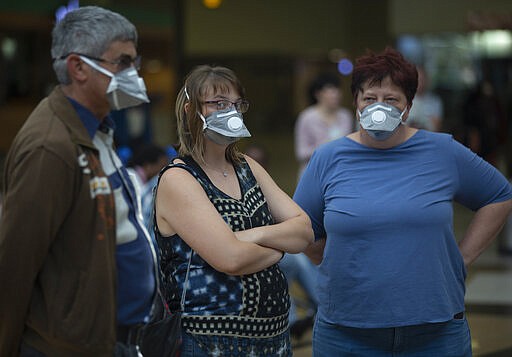 People wearing masks wait for passengers at Johannesburg's O.R. Tambo International Airport, Monday, March 16, 2020 a day after President Cyril Ramaphosa declared a national state of disaster. Ramaphosa said all schools will be closed for 30 days from Wednesday and he banned all public gatherings of more than 100 people. South Africa will close 35 of its 53 land borders and will intensify screening at its international airports. For most people, the new COVID-19 coronavirus causes only mild or moderate symptoms. For some it can cause more severe illness. (AP Photo/Denis Farrell)