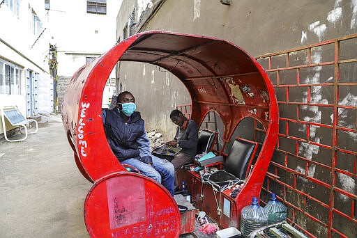 Francis Kimani Waweru sits in his shoeshine stall, which he complains has seen few customers since fears of the new coronavirus took hold, on a street in downtown Nairobi, Kenya Friday, March 20, 2020. For most people, the new coronavirus causes only mild or moderate symptoms such as fever and cough and the vast majority recover in 2-6 weeks but for some, especially older adults and people with existing health issues, the virus that causes COVID-19 can result in more severe illness, including pneumonia. (AP Photo/Patrick Ngugi)