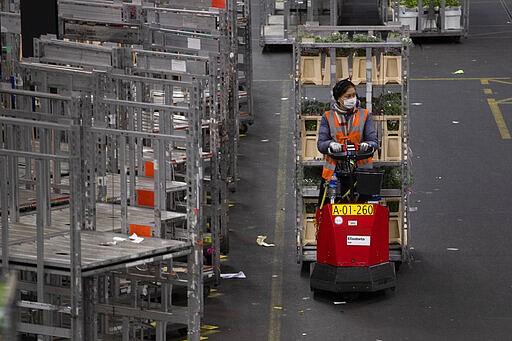 A worker with a face mask shifts flowers around a warehouse as empty racks are seen at flower auctioneer Royal FloraHolland in Aalsmeer, Netherlands, Thursday, March 19, 2020. Sales at major Dutch growers have slumped, forcing farmers to destroy their flower crops in this busy spring season when bulb fields erupt into color.  For many people the new coronavirus pandemic causes mild or moderate symptoms but for some it can cause severe illness. (AP Photo/Peter Dejong)