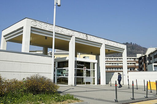 FILE - In this Tuesday, March 17, 2020 filer, a woman walks outside the Pesenti Fenaroli hospital, in Alzano Lombardo, near Bergamo, the heart of the hardest-hit province in Italy&#146;s hardest-hit region of Lombardy, Italy. For most people, the new coronavirus causes only mild or moderate symptoms. For some it can cause more severe illness, especially in older adults and people with existing health problems. (AP Photo/Luca Bruno, File)