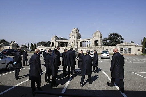 FILE - In this Tuesday, March 17, 2020 file photo, pallbearers stand outside the Monumentale cemetery, in Bergamo, the heart of the hardest-hit province in Italy&#146;s hardest-hit region of Lombardy, Italy. For most people, the new coronavirus causes only mild or moderate symptoms. For some it can cause more severe illness, especially in older adults and people with existing health problems. (AP Photo/Luca Bruno, File)