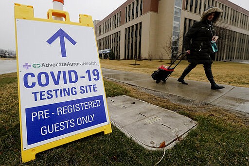 FILE - In this Wednesday, March 18, 2020 file photo, a pedestrian walks past a COVID-19 testing sign at Advocate Lutheran General Hospital in Park Ridge, Ill. Some bored with the limitations of the term &quot;COVID-19&quot; and the even clunkier name of the virus that causes it &#151; severe acute respiratory syndrome coronavirus 2 &#151; have come up with their own shorthand. On Thursday, Eric Acton, a linguist at Eastern Michigan University, said, &#147;One of my students just referred to the virus as &#147;The Ronies,&#148; after a research group meeting conducted virtually. (AP Photo/Nam Y. Huh)