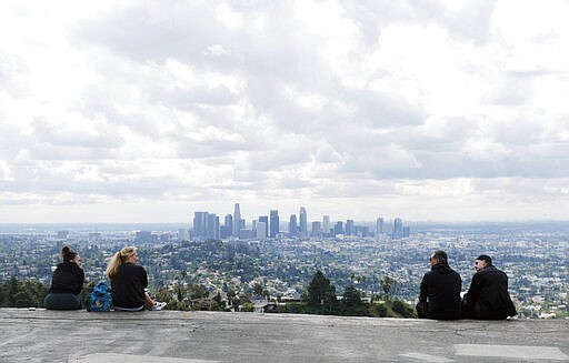 Two pairs of hikers maintain distance as they mingle at Vista View Point in Griffith Park, Friday, March 20, 2020, in Los Angeles. California Gov. Gavin Newsom issued a statewide stay-at-home order Thursday for residents to venture outside only for essential jobs, errands and some exercise, due to coronavirus concerns. (AP Photo/Chris Pizzello)