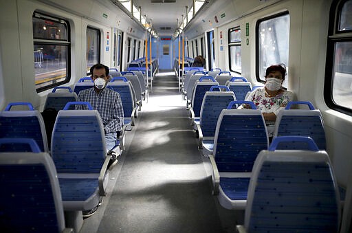 People wearing masks, as a precaution against the spread of the new coronavirus, ride an empty train in Buenos Aires, Argentina, Friday, March 20, 2020. Argentina's government has ordered residents to quarantine themselves until the end of the month to help contain the spread of COVID-19. (AP Photo/Natacha Pisarenko)