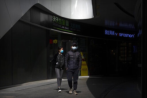 People wear face masks as they walk through an office complex in Beijing, Friday, March 20, 2020. Italy's deaths from the coronavirus pandemic eclipsed China's on Thursday as the scourge extended its march across the West, where the United States and other countries increasingly enlisted the military to prepare for an onslaught of patients and California's governor ordered people in the most-populous U.S. state to stay home. The virus causes only mild or moderate symptoms, such as fever and cough, for most people, but severe illness is more likely in the elderly and people with existing health problems. (AP Photo/Mark Schiefelbein)