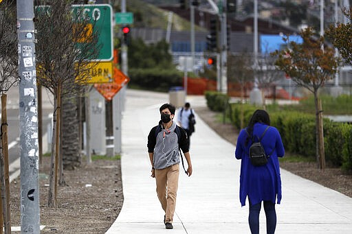 A man wears a mask after crossing from Tijuana, Mexico, at the San Isidro port of entry Friday, March 20, 2020, in San Diego. Mexico and the U.S. announced Friday that they would prohibit all &quot;non-essential&quot; travel across their shared border as part of efforts to control the spread of the coronavirus. (AP Photo/Gregory Bull)