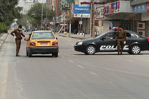 An Iraqi police a checkpoint near shops that are shuttered to help prevent the spread of the coronavirus, in Baghdad, Iraq Friday, March 20, 2020. Iraq, authorities struggled to keep pilgrims from marking the annual Shiite Muslim commemoration of the death of Imam Mousa al-Kazim despite a week-long curfew in the capital. Thousands of Iraqis typically make the journey on foot to the shrine of the imam in the Khazimiyah area of Baghdad.   For most people, the virus causes only mild or moderate symptoms. For some it can cause more severe illness. (AP Photo/Hadi Mizban)