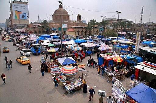 In this Monday, March 16, 2020 photo, people shop in the main Shurja market in central Baghdad, Iraq. The economic fallout from the new coronavirus coupled with a sudden drop in oil prices threatens to catapult Iraq into an unprecedented crisis. The crude-exporting country is struggling to finance measures to contain the COVID-19 pandemic amid a leadership void in the federal government. (AP Photo/Khalid Mohammed)