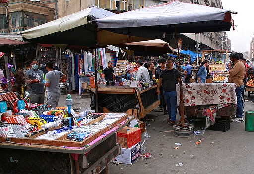 In this Monday, March 16, 2020 photo, people shop in the main Shurja market in central Baghdad, Iraq. The economic fallout from the new coronavirus coupled with a sudden drop in oil prices threatens to catapult Iraq into an unprecedented crisis. The crude-exporting country is struggling to finance measures to contain the COVID-19 pandemic amid a leadership void in the federal government. (AP Photo/Khalid Mohammed)