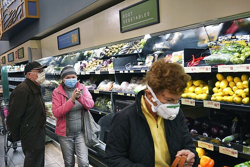 Customers wearing protective masked shop the fresh produce section at Gelson's supermarket that opened special morning hours to serve seniors 60-years and older due to coronavirus concerns, Friday, March 20, 2020, in the Sherman Oaks section of Los Angeles on Friday, March 20, 2020. California's 40 million people are all but confined to their homes in the nation's biggest lockdown yet, as America's governors watch with growing alarm as southern Europe buckles under the strain of the coronavirus outbreak. (AP Photo/Richard Vogel)