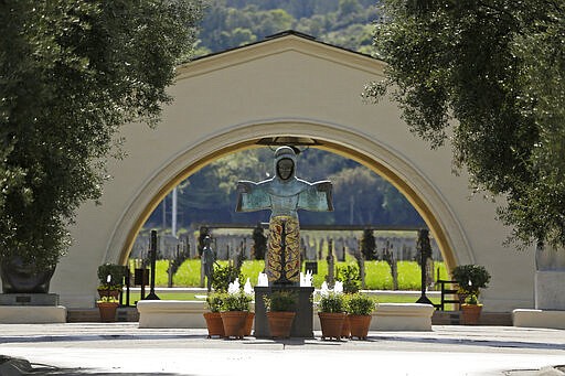 In this photo taken Thursday, March 19, 2020, a sculpture of St. Francis of Assisi, created by Beniamino Bufano, looks out over the empty entryway to the Robert Mondavi Winery in Oakville, Calif. Wineries in the Napa Valley are closed due to coronavirus restrictions expect for production, but some allow customers to pick up shipments of wine and for direct purchases. (AP Photo/Eric Risberg)