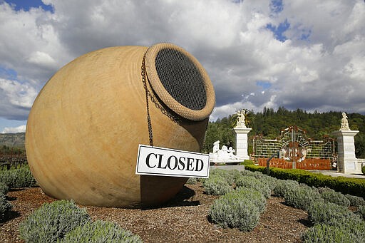 In this photo taken Thursday, March 19, 2020, a closed sign is posted outside the driveway to the Piazza Del Dotto Winery &amp; Caves in Napa, Calif. Wineries in the Napa Valley are closed due to coronavirus restrictions except for production, but some allow customers to pick up shipments of wine and for direct purchases. (AP Photo/Eric Risberg)