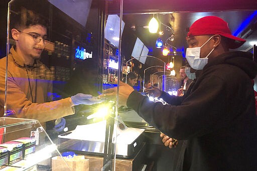 A customer who wished to remain unidentified, right, wears a mask while shopping at The Green Cross cannabis dispensary in San Francisco, Wednesday, March 18, 2020. As about 7 million people in the San Francisco Bay Area are under shelter-in-place orders, only allowed to leave their homes for crucial needs in an attempt to slow the virus spread, marijuana stores remain open and are being considered &quot;essential services.&quot; (AP Photo/Haven Daley)