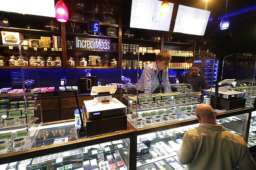 Budtenders at The Green Cross cannabis dispensary help customers in San Francisco, Wednesday, March 18, 2020. As about 7 million people in the San Francisco Bay Area are under shelter-in-place orders, only allowed to leave their homes for crucial needs in an attempt to slow virus spread, marijuana stores remain open and are being considered &quot;essential services.&quot; (AP Photo/Jeff Chiu)