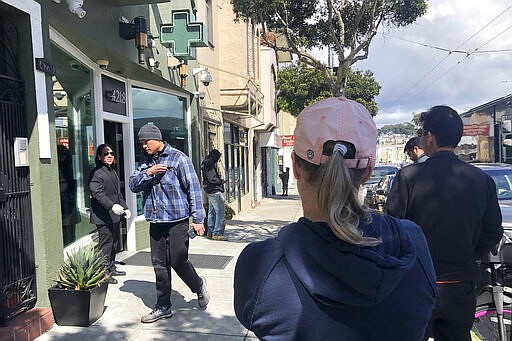 Customers maintain social distance while waiting to enter The Green Cross cannabis dispensary in San Francisco, Wednesday, March 18, 2020. As about 7 million people in the San Francisco Bay Area are under shelter-in-place orders, only allowed to leave their homes for crucial needs in an attempt to slow virus spread, marijuana stores remain open and are being considered &quot;essential services.&quot; (AP Photo/Haven Daley)