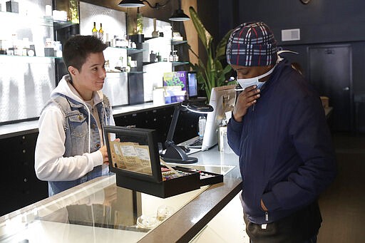 Customer Antoine Conners, right, wears a mask while being helped by budtender Chris Gomez at The Mission Cannabis Club dispensary in San Francisco, Thursday, March 19, 2020. (AP Photo/Jeff Chiu)