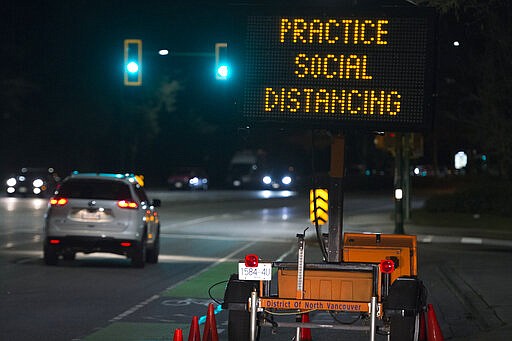 FILE - In this Wednesday, March 18, 2020 file photo, a sign reminding people about &quot;social distancing&quot; in the midst of the COVID-19 coronavirus outbreak stands next to a roadway in North Vancouver, British Columbia, Canada. Many see &#147;social distancing&#148; to be the greatest pandemic-era addition the vernacular yet &#151; easily understood phrasing that&#146;s helped communicate to millions that they need to keep a safe berth to avoid spreading the virus. (Jonathan Hayward/The Canadian Press via AP)