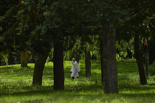 A member of the health service at Txagorritxu hospital walks along the perimeter of the hospital, in Vitoria, northern Spain, Vitoria, northern Spain, March 20, 2020. Spain will mobilize 200 billion euros or the equivalent to one fifth of the country's annual output in loans, credit guarantees and subsidies for workers and vulnerable citizens, Prime Minister Pedro Sanchez announced Tuesday. For most people, the new coronavirus causes only mild or moderate symptoms. For some, it can cause more severe illness, especially in older adults and people with existing health problems. (AP Photo/Alvaro Barrientos)