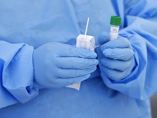 A healthcare worker prepares to collect a sample to test for COVID-19 at a drive-through testing site Friday, March 20, 2020, at the Doris Ison Health Center in Miami. (AP Photo/Wilfredo Lee)