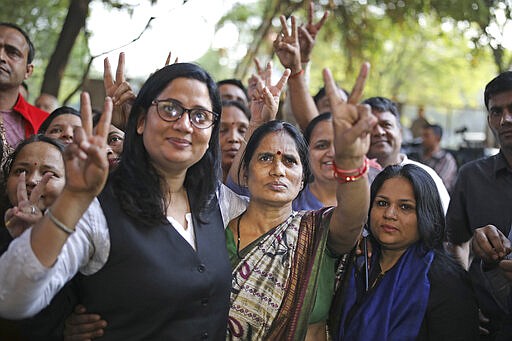 Asha Devi, center, mother of the victim of the fatal 2012 gang rape on a moving bus, displays a victory sign with her lawyer after the rapists of her daughter were hanged in New Delhi, India, Friday, March 20, 2020. Four men were sentenced to capital punishment for the 2012 gang-rape of a 23-year-old physiotherapy student on a moving bus in New Delhi have been executed. (AP Photo/Altaf Qadri)