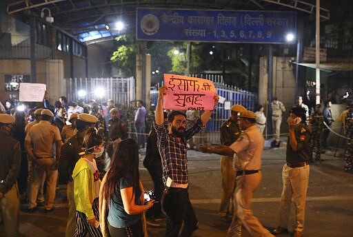 An Indian carrying a banner which reads dawn of Justice, walks past the entrance of Tihar central prison where four men were sentenced to capital punishment in New Delhi, India, Friday, March 20, 2020. Four men sentenced to death for the gruesome gang rape and murder of a woman on a New Delhi bus in 2012 were hanged Friday, concluding a case that exposed the scope of sexual violence against women in India and prompted horrified Indians to demand swift justice. (AP Photo/Manish Swarup)