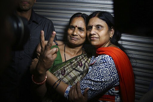 Asha Devi, left, mother of the victim of the fatal 2012 gang rape on a moving bus, displays a victory sign with her sister after the rapists of her daughter were hanged, in New Delhi, India, Friday, March 20, 2020. Four men were sentenced to capital punishment for the 2012 gang-rape of a 23-year-old physiotherapy student on a moving bus in New Delhi have been executed. (AP Photo/Altaf Qadri)