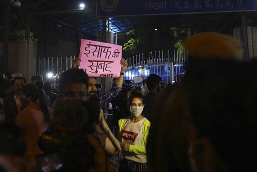 An Indian carrying a banner which reads dawn of Justice, with a woman stand outside Tihar central prison where four men were sentenced to capital punishment in New Delhi, India, Friday, March 20, 2020. Four men sentenced to death for the gruesome gang rape and murder of a woman on a New Delhi bus in 2012 were hanged Friday, concluding a case that exposed the scope of sexual violence against women in India and prompted horrified Indians to demand swift justice. (AP Photo/Manish Swarup)