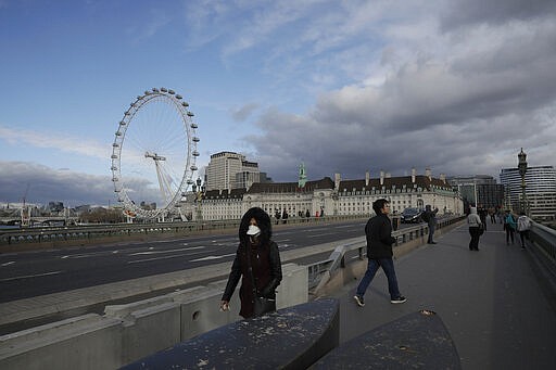 A woman wearing a face mask walks over a near empty Westminster Bridge backdropped by the London Eye ferris wheel in central London, Friday, March 20, 2020. For most people, the new coronavirus causes only mild or moderate symptoms, such as fever and cough. For some, especially older adults and people with existing health problems, it can cause more severe illness, including pneumonia. (AP Photo/Matt Dunham)