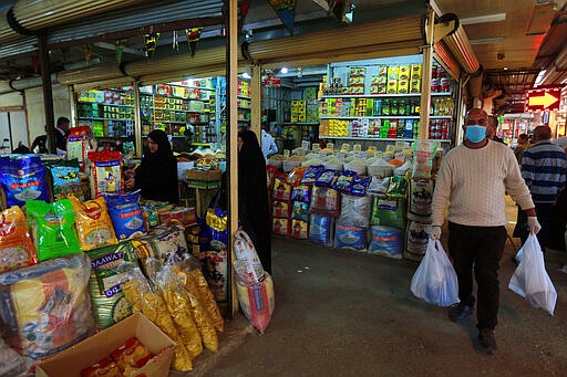 In this Tuesday, March 10, 2020 photo, people shop in the main Shurja market, in central Baghdad, Iraq. The economic fallout from the new coronavirus coupled with a sudden drop in oil prices threatens to catapult Iraq into an unprecedented crisis. The crude-exporting country is struggling to finance measures to contain the COVID-19 pandemic amid a leadership void in the federal government. (AP Photo/Hadi Mizban)