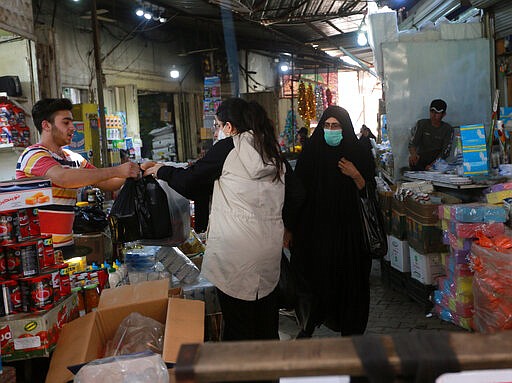 In this Tuesday, March 10, 2020 photo, people shop in the main Shurja market in central Baghdad, Iraq. The economic fallout from the new coronavirus coupled with a sudden drop in oil prices threatens to catapult Iraq into an unprecedented crisis. The crude-exporting country is struggling to finance measures to contain the COVID-19 pandemic amid a leadership void in the federal government. (AP Photo/Hadi Mizban)