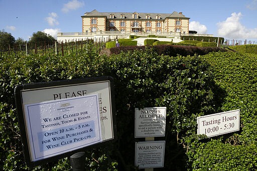 A sign outside the Domaine Carneros winery tells people they are closed for tastings and tours, but open for purchases and wine club pickups Thursday, March 19, 2020, in Napa, Calif. As worries about the spread of the coronavirus confine millions of Californians to their homes, concern is growing about those who have no homes in which to shelter. (AP Photo/Eric Risberg)