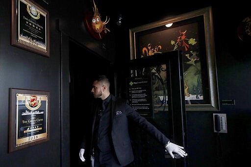 The Green Cross cannabis dispensary employee Ruben Arias watches the number of customers in the showroom in San Francisco, Wednesday, March 18, 2020. As about 7 million people in the San Francisco Bay Area are under shelter-in-place orders, only allowed to leave their homes for crucial needs in an attempt to slow virus spread, marijuana stores remain open and are being considered &quot;essential services.&quot; (AP Photo/Jeff Chiu)