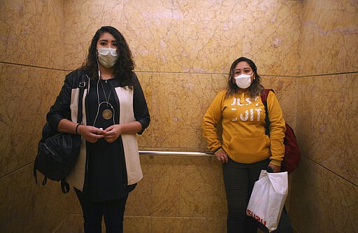 Women wear face masks as a precaution against the spread of the new coronavirus as they ride the elevator to their offices in Mexico City, Thursday, March 19, 2020. (AP Photo/Marco Ugarte)