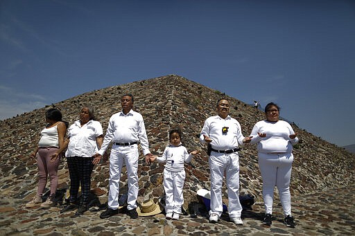 The Martinez family from Puebla celebrates the Spring equinox a little early, to avoid crowds and closures, atop the Pyramid of the Sun, in Teotihuacan, Mexico, Thursday, March 19, 2020. To slow the spread of the new coronavirus, authorities announced Wednesday that they would close the pyramid complex on weekends, beginning Saturday, March 21, when thousands of visitors typically climb the Pyramid of the Sun to celebrate the Spring equinox.(AP Photo/Rebecca Blackwell)