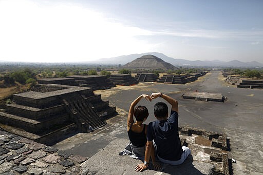 South Korean tourists Myung Hee Lee, left, and Byung Ho Im, form a heart with their hands as they pose for pictures atop the Pyramid of the Moon, in Teotihuacan, Mexico, Thursday, March 19, 2020. The pair took advantage of getting stuck in Mexico City for a day to visit the pyramids, after their flight home from a vacation in Cancun and Cuba was cancelled. To slow the spread of the new coronavirus, authorities announced Wednesday that they would close the pyramid complex on weekends, beginning Saturday, March 21, when thousands of visitors typically climb the Pyramid of the Sun to celebrate the Spring equinox.(AP Photo/Rebecca Blackwell)