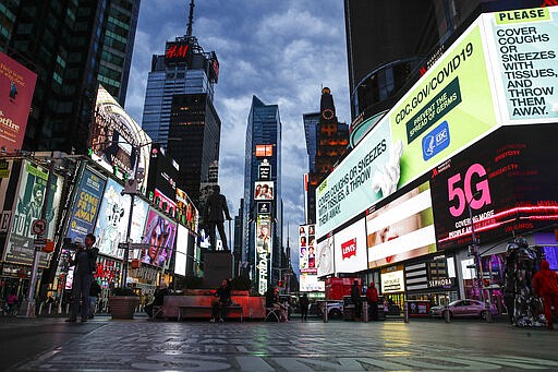 A screen displaying messages concerning COVID-19 is seen in a sparsely populated Times Square, Friday, March 20, 2020, in New York. New York Gov. Andrew Cuomo is ordering all workers in non-essential businesses to stay home and banning gatherings statewide. &quot;Only essential businesses can have workers commuting to the job or on the job,&quot; Cuomo said of an executive order he will sign Friday. Nonessential gatherings of individuals of any size or for any reason are canceled or postponed. (AP Photo/John Minchillo)