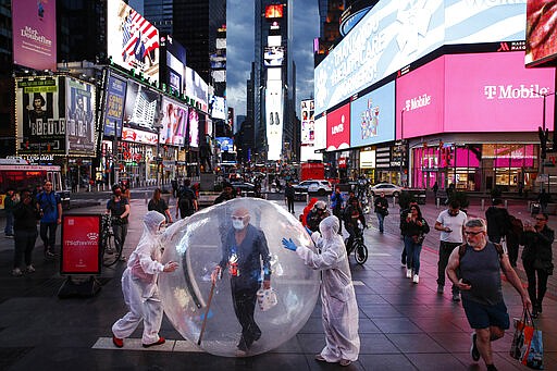 Artists perform under a billboard displaying thanks to healthcare workers due to COVID-19 concerns in a sparsely populated Times Square, Friday, March 20, 2020, in New York. New York Gov. Andrew Cuomo is ordering all workers in non-essential businesses to stay home and banning gatherings statewide. &quot;Only essential businesses can have workers commuting to the job or on the job,&quot; Cuomo said of an executive order he will sign Friday. Nonessential gatherings of individuals of any size or for any reason are canceled or postponed. (AP Photo/John Minchillo)