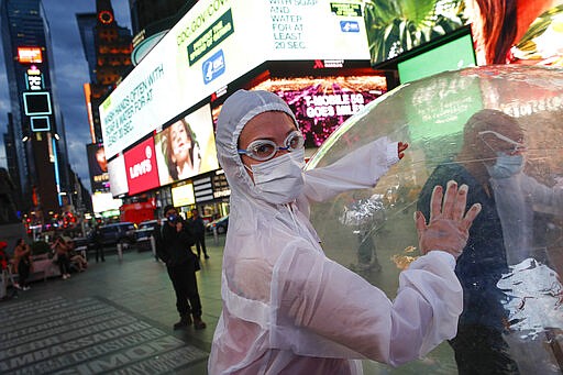 Artists perform under a billboard displaying information on COVID-19 in a sparsely populated Times Square, Friday, March 20, 2020, in New York. New York Gov. Andrew Cuomo is ordering all workers in non-essential businesses to stay home and banning gatherings statewide. &quot;Only essential businesses can have workers commuting to the job or on the job,&quot; Cuomo said of an executive order he will sign Friday. Nonessential gatherings of individuals of any size or for any reason are canceled or postponed. (AP Photo/John Minchillo)