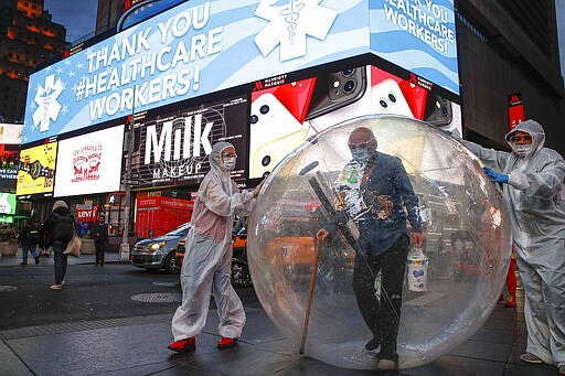 Artists perform under a billboard displaying thanks to healthcare workers due to COVID-19 concerns in a sparsely populated Times Square, Friday, March 20, 2020, in New York. New York Gov. Andrew Cuomo is ordering all workers in non-essential businesses to stay home and banning gatherings statewide. &quot;Only essential businesses can have workers commuting to the job or on the job,&quot; Cuomo said of an executive order he will sign Friday. Nonessential gatherings of individuals of any size or for any reason are canceled or postponed. (AP Photo/John Minchillo)