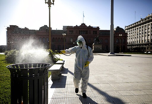 A man sprays bleach at Plaza de Mayo in Buenos Aires, Argentina, Friday, March 20, 2020. Argentina's government imposed a countrywide lockdown to contain the spread of the coronavirus. (AP Photo/Natacha Pisarenko)