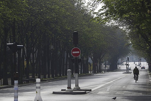 A man rides a bicycle in an empty street of Paris, Friday, March 20, 2020. French President Emmanuel Macron said that for 15 days starting at noon on Tuesday, people will be allowed to leave the place they live only for necessary activities such as shopping for food, going to work or taking a walk. For most people, the new coronavirus causes only mild or moderate symptoms. For some it can cause more severe illness, especially in older adults and people with existing health problems. (AP Photo/Thibault Camus)