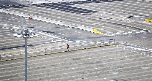 A man walks through empty passenger lanes at the Port of Dover, south east England, Friday March 20, 2020. For most people, the new coronavirus causes only mild or moderate symptoms, such as fever and cough. For some, especially older adults and people with existing health problems, it can cause more severe illness, including pneumonia. (Gareth Fuller/PA via AP)