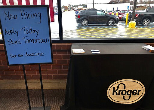 FILE - In this March 18, 2020 file photo, a sign encouraging job seekers to apply stands in a suburban Cincinnati Kroger store.  Kroger Co. joins a growing list of retail and restaurant chains offering special bonuses or sweetening benefits to workers. The grocery chain said that full-time hourly workers will receive a one-time special bonus of $300, while part-time workers will receive $150. (AP Photo/Dan Sewell, File)