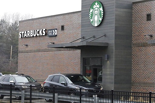 Customers wait for their order in their car at a Starbucks in Northbrook, Ill., Monday, March 16, 2020. Starbucks announced Sunday its company-owned stores across the U.S and Canada will shift to a &quot;to go&quot; model for at least two weeks to encourage social distancing. While customers can still walk up to the counter and order, there will be no seating in stores. (AP Photo/Nam Y. Huh)