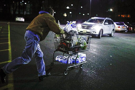 Customer Harry Westhoff, 71, runs his groceries back to his car after shopping at a Stop &amp; Shop supermarket that opened special morning hours to serve people 60-years and older due to coronavirus concerns, Friday, March 20, 2020, in Teaneck, N.J. For most people, COVID-19, the disease caused by the new coronavirus, causes only mild or moderate symptoms, such as fever and cough. For some, especially older adults and people with existing health problems, it can cause more severe illness, including pneumonia. (AP Photo/John Minchillo)