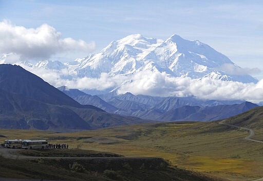 FILE - In this Aug. 26, 2016, file photo sightseeing buses and tourists are seen at a pullout popular for taking in views of North America's tallest peak, Denali, in Denali National Park and Preserve, Alaska. No permits have been issued to climb Denali or Mount Foraker this year. The climbing season in the national park about 180 miles (290 kilometers) north of Anchorage usually begins in late April and ends in mid-July. Refunds will be issued to those who have started the registration process. (AP Photo/Becky Bohrer, File)