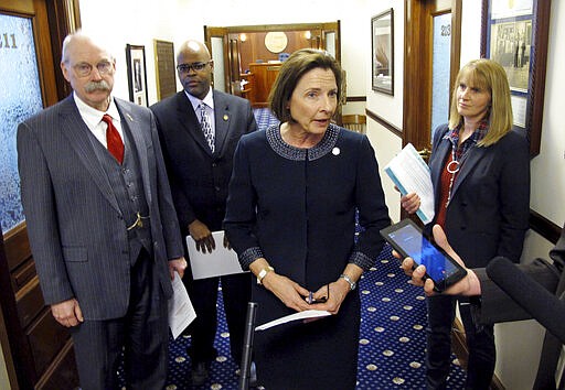 FILE - In this March 11, 2020 file photo Alaska Senate President Cathy Giessel, center, speaks to reporters in Juneau, Alaska. Alaska Senate leaders said Friday, March 20, 2020, that lawmakers are pushing to complete their most pressing work in the coming days, as concerns about the coronavirus persist. Giessel, an Anchorage Republican, said the hope is that this could be done within a week. Priority bills include state budgets, negotiations on which in the past have gotten messy. Also pictured, from left, are Sens. Bert Stedman, David Wilson and Natasha von Imhof. (AP Photo/Becky Bohrer,File)